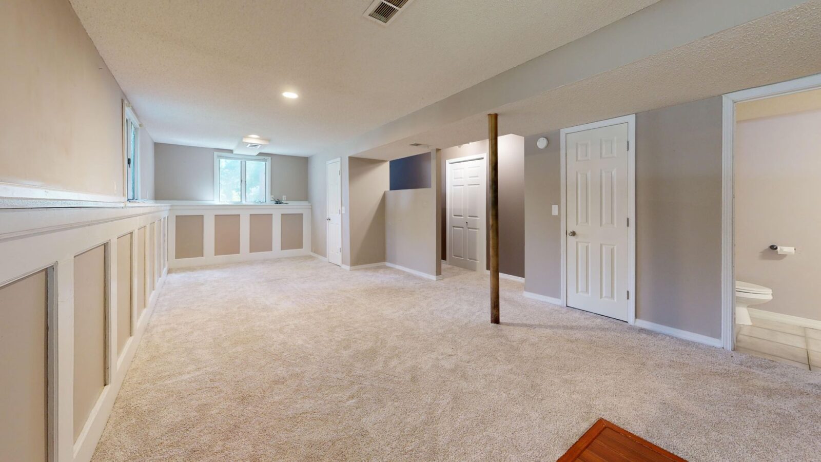 White portable dehumidifier running in a finished basement with hardwood shelving and a small hygrometer nearby