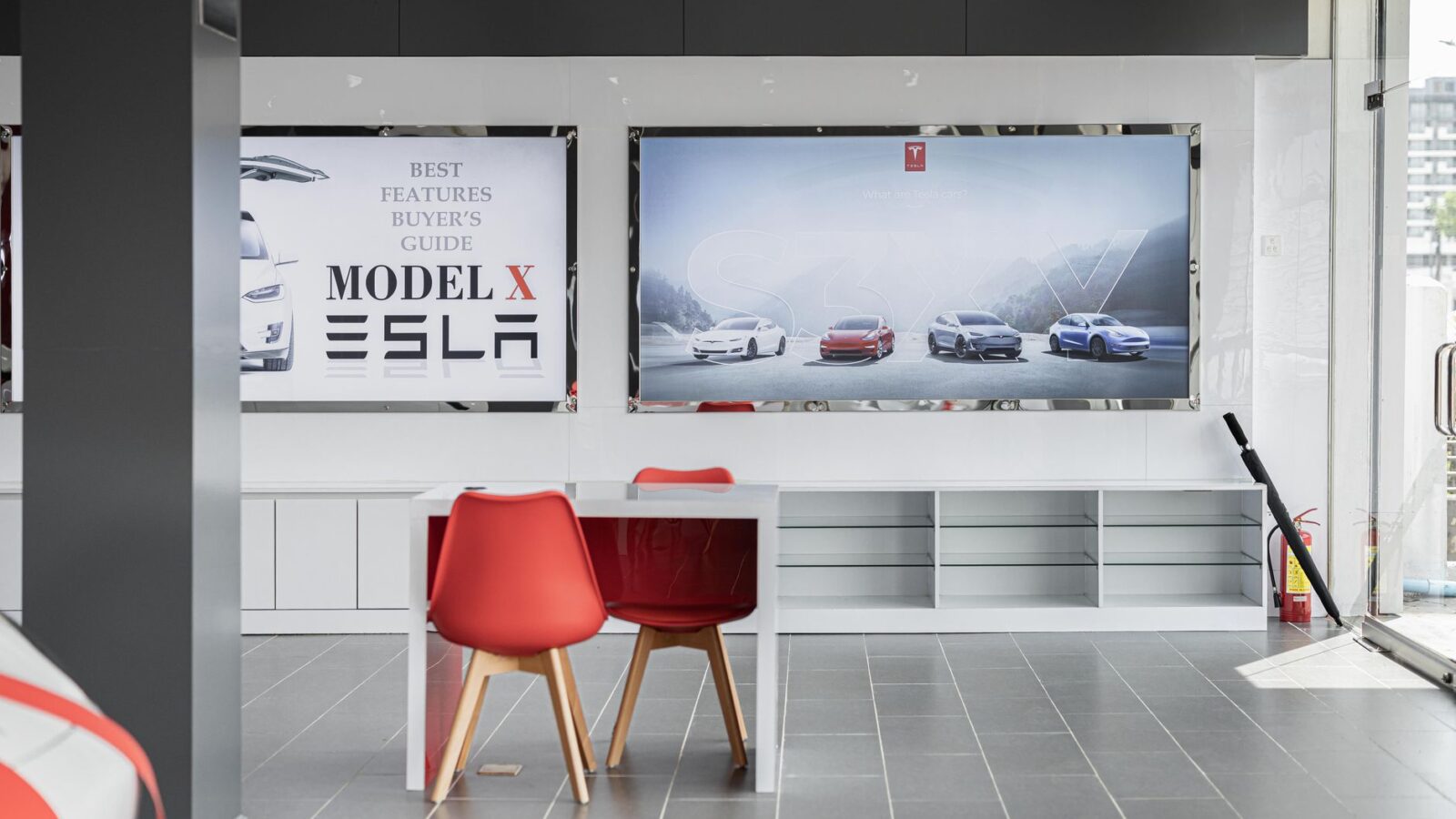 Row of new electric vehicles parked inside a modern car dealership showroom with large windows
