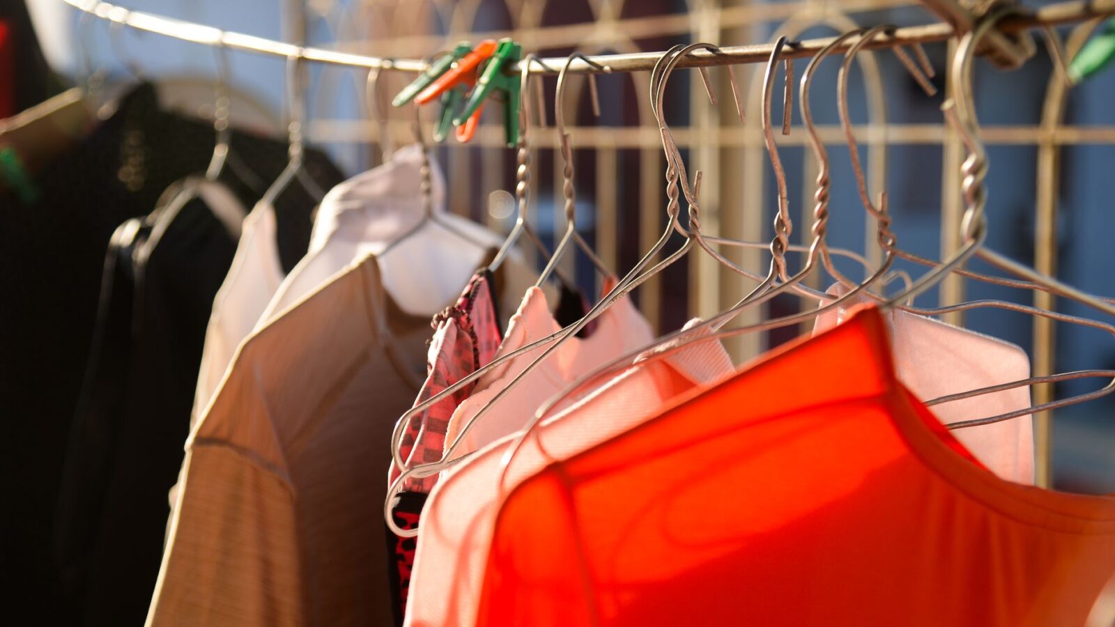 Wet cotton shirts and towels drying on a retractable indoor clothesline in a sunlit home laundry area.