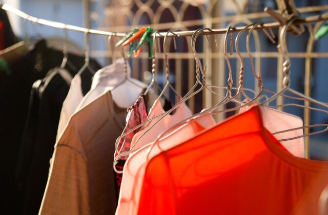 Wet cotton shirts and towels drying on a retractable indoor clothesline in a sunlit home laundry area.